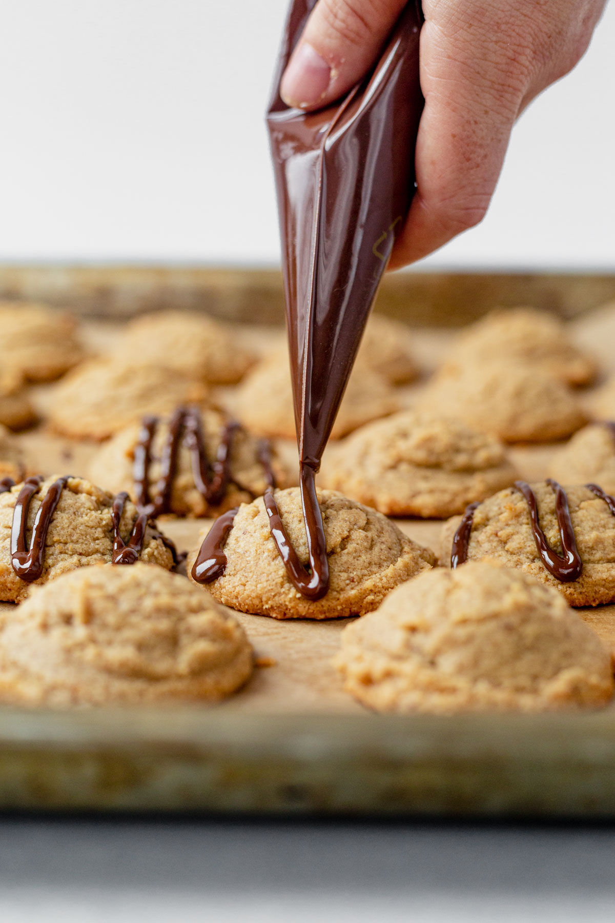 melted chocolate drizzling over a peanut butter cookie with almond flour