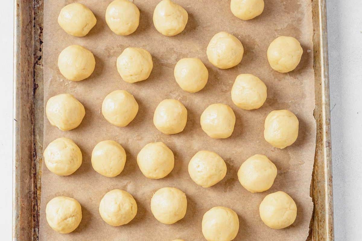 Italian sprinkle cookie dough balls rolled into smooth balls on a cookie sheet
