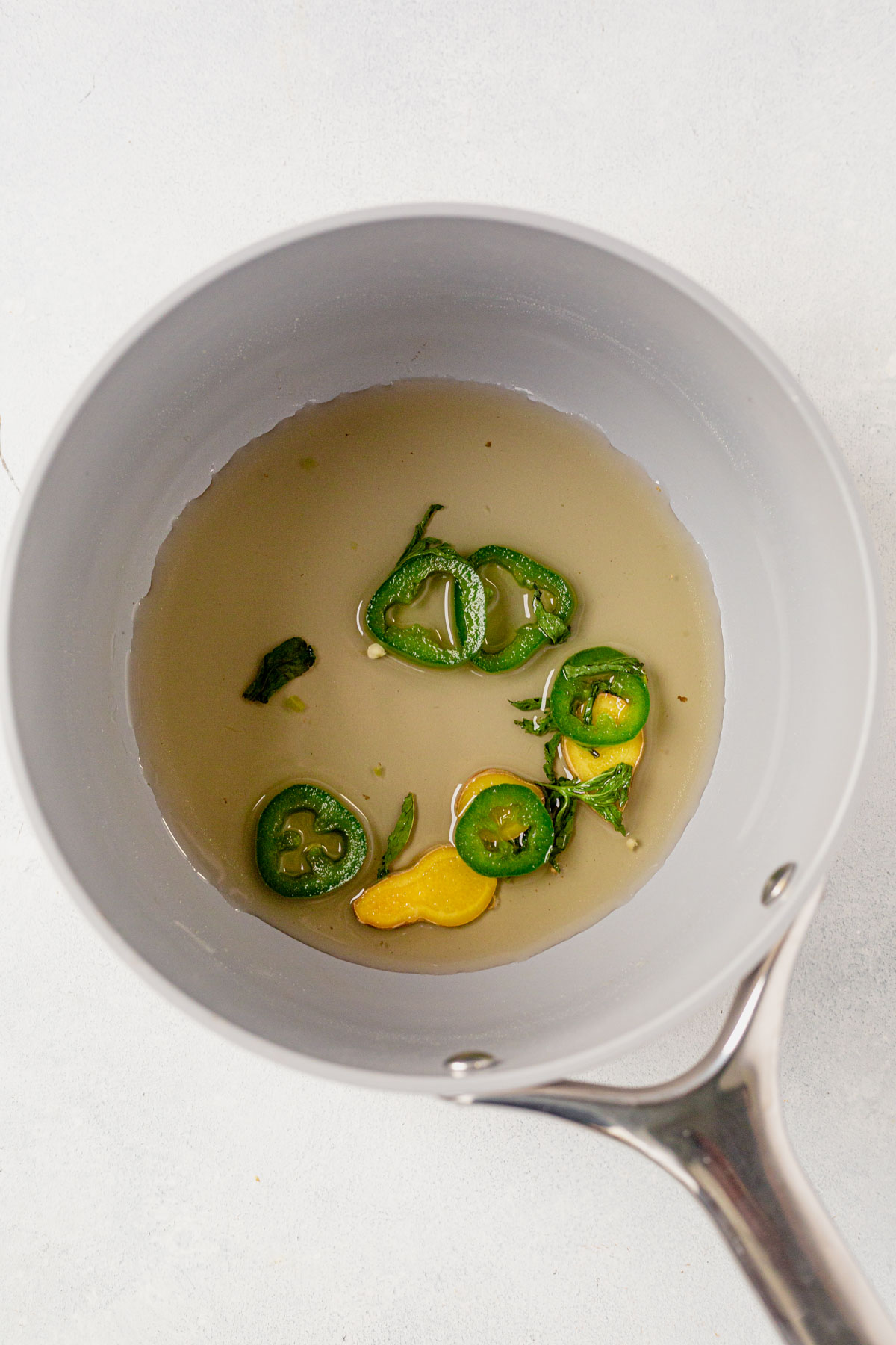 simple syrup in a saucepan with jalapeno, ginger and mint