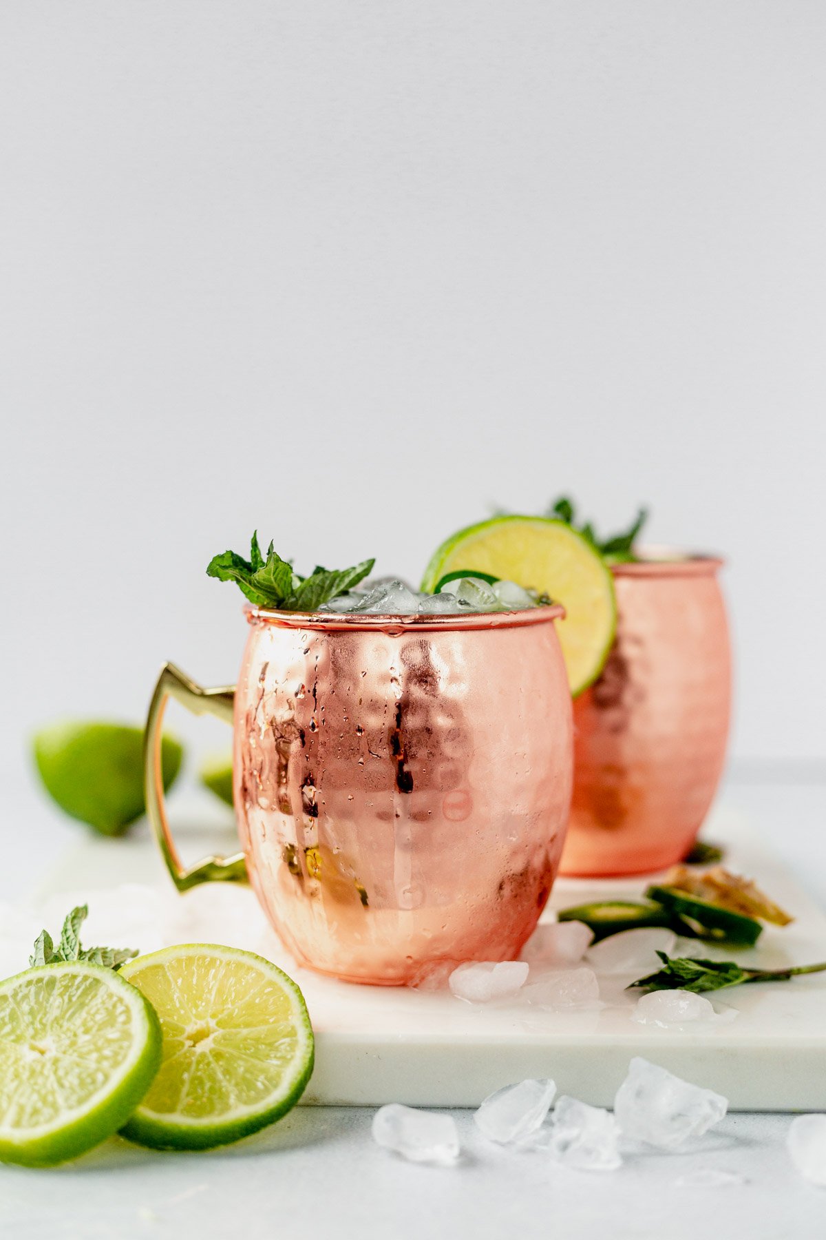two moscow mules with tequila in copper cups with lime wedges