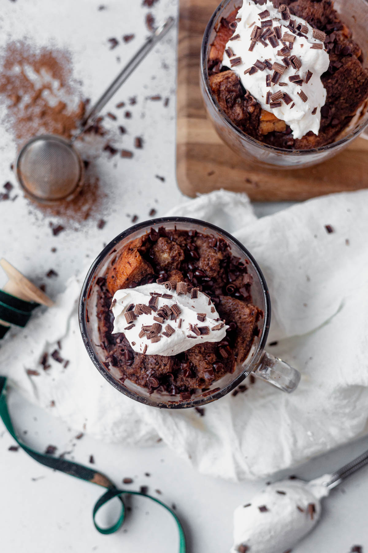 two mugs of microwave bread pudding topped with whipped cream and chocolate