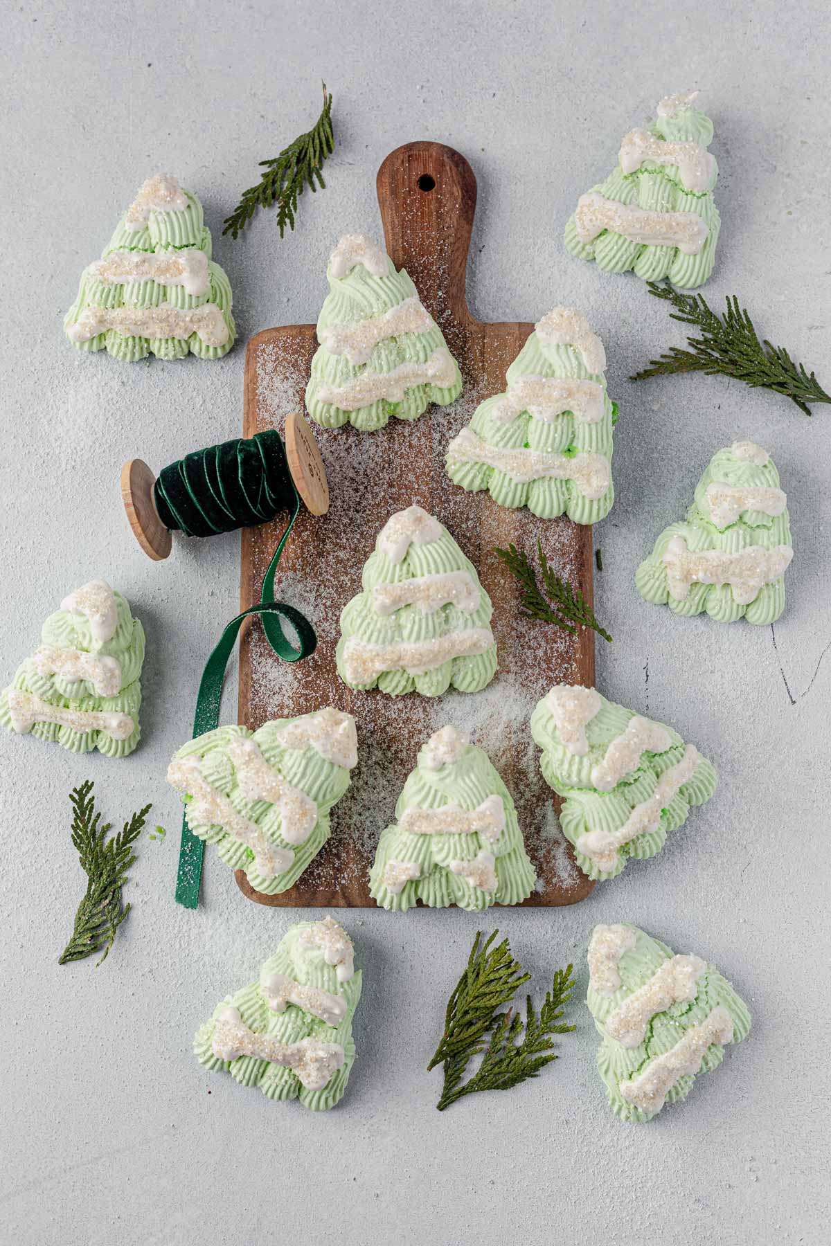 a batch of mini meringue christmas trees served on a wooden board 