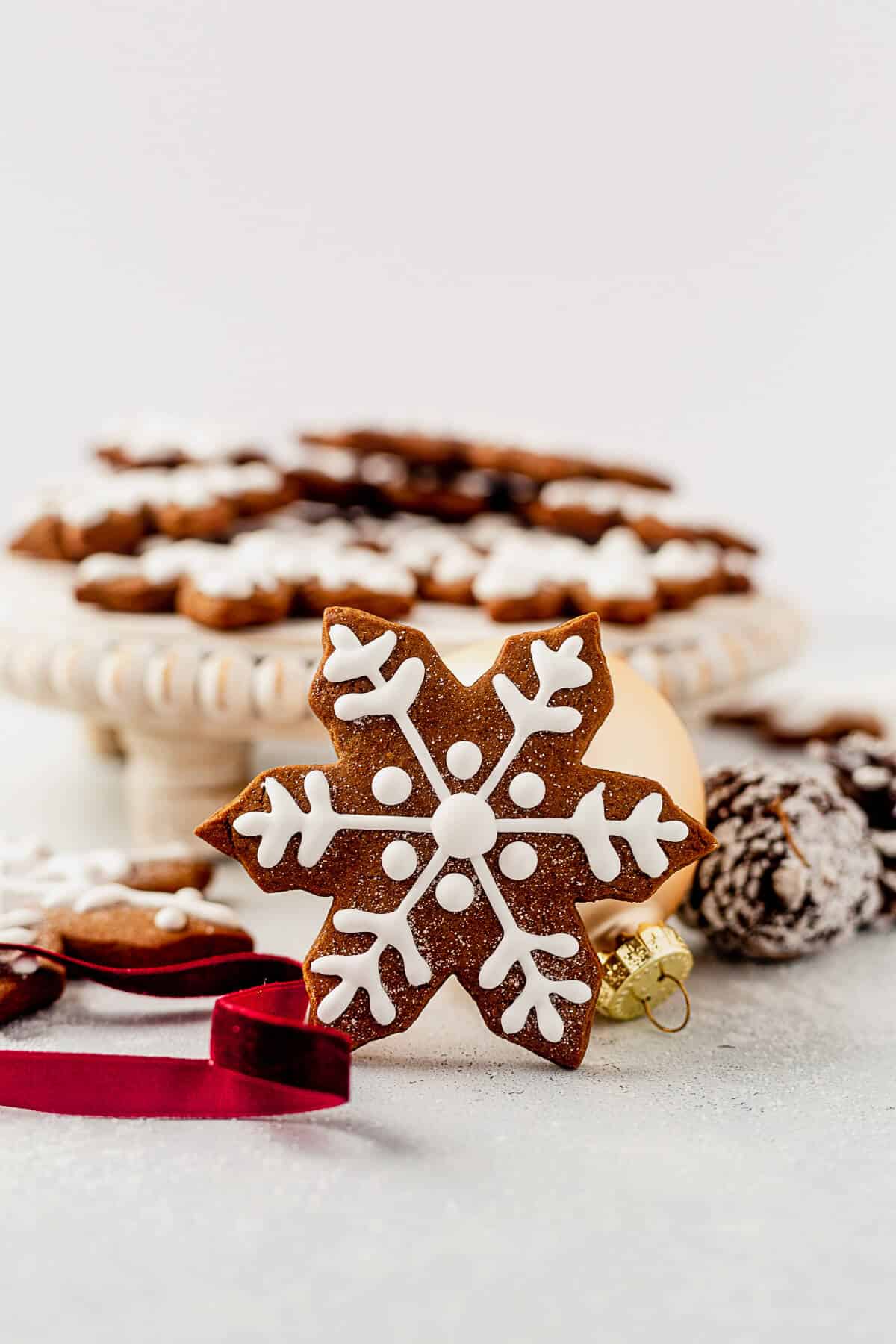 a gingerbread snowflake cookie standing up against a tray of more cookies