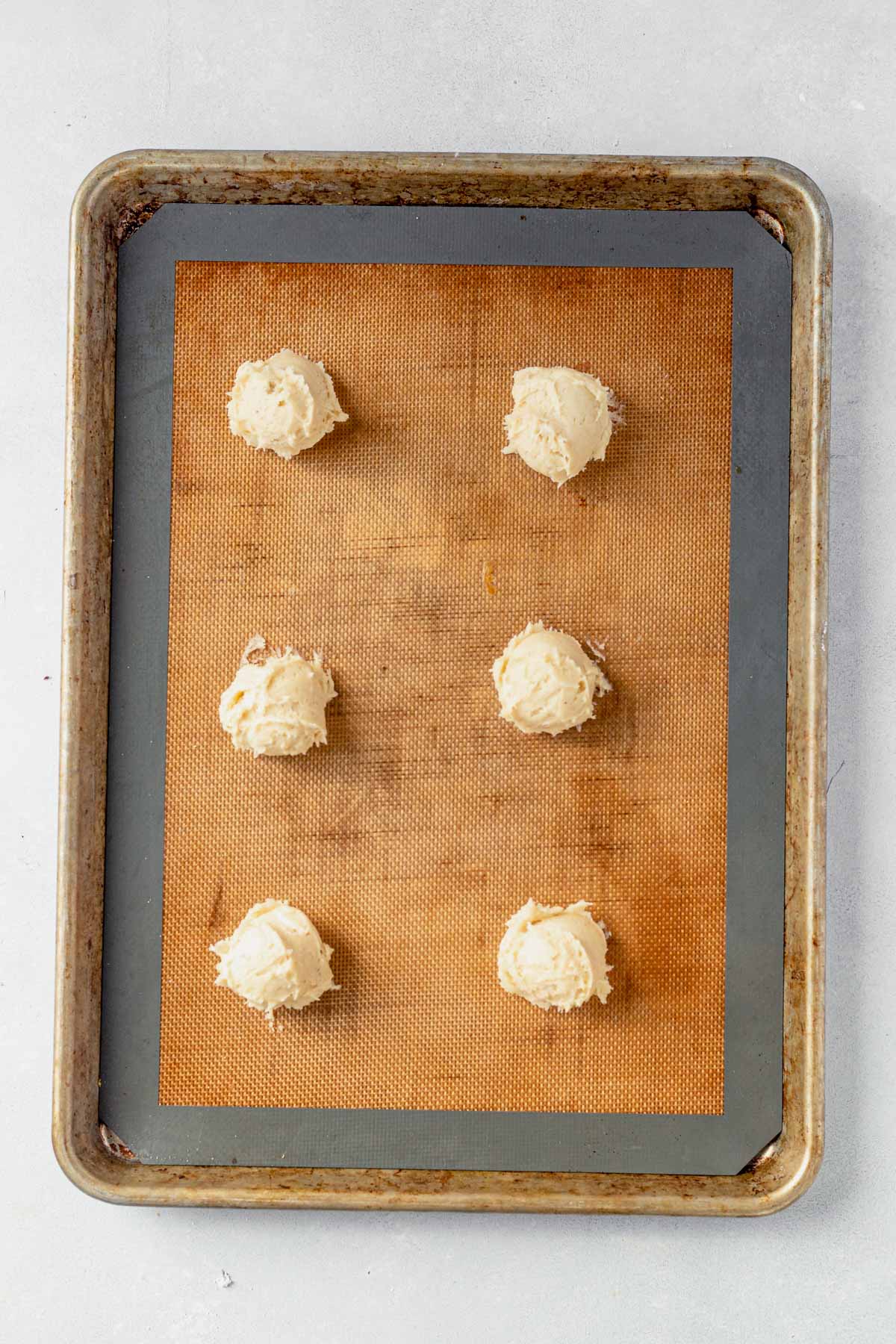 eggnog cookie dough dropped on a large baking sheet with a silpat mat