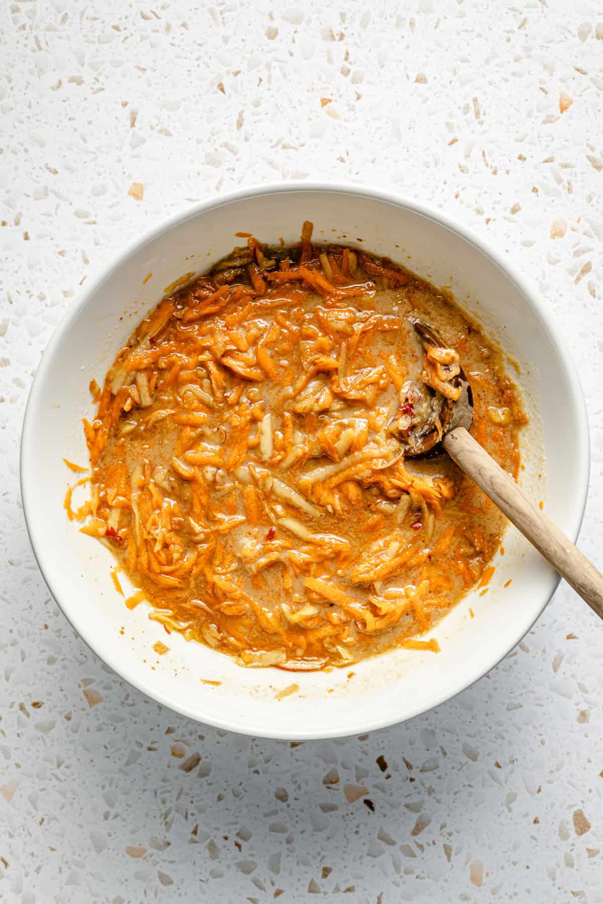 shredded apple, carrots, and wet ingreidents for muffins mixed in a bowl.