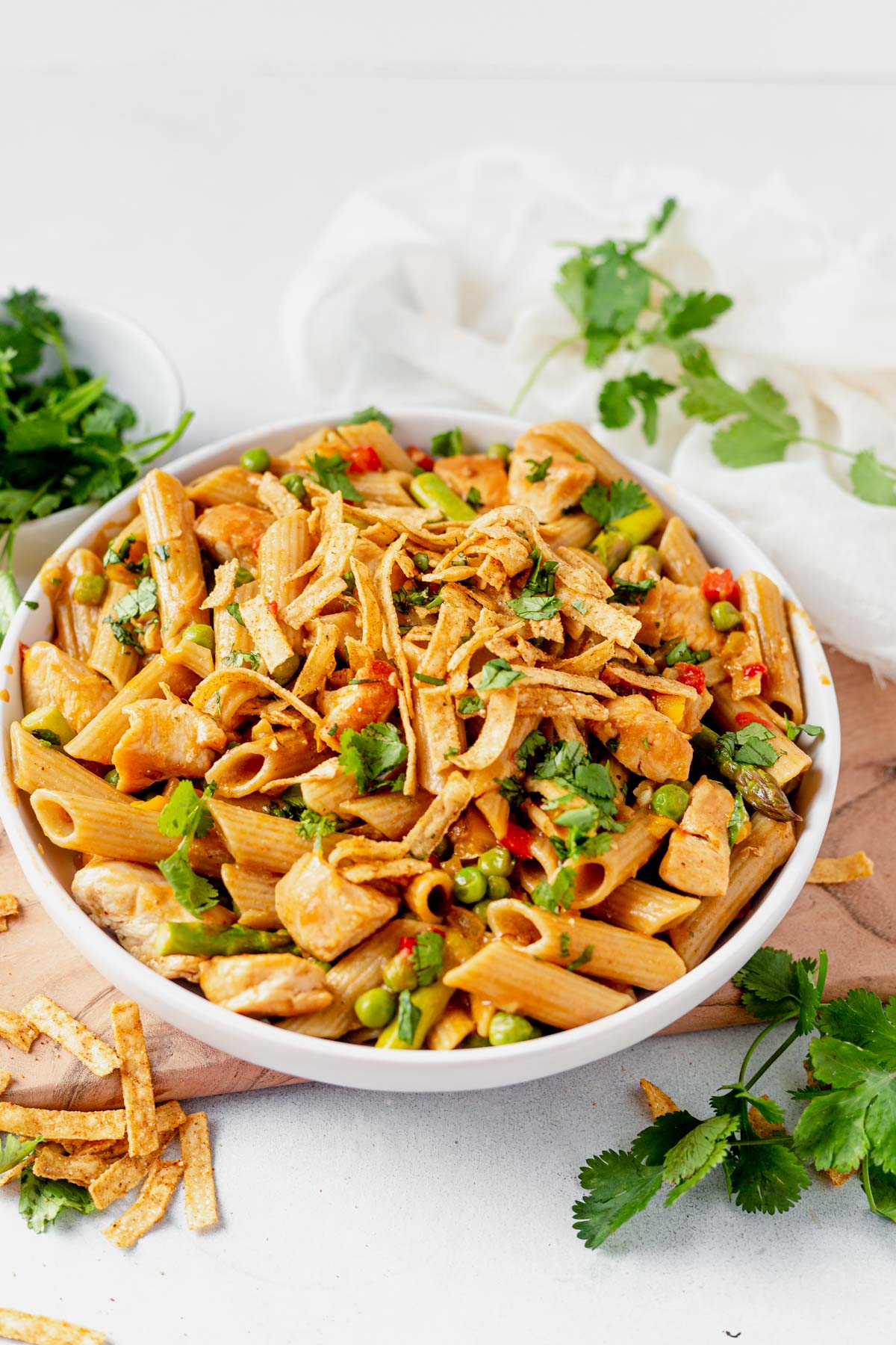 a bowl of spicy chicken chipotle pasta with tortilla strips and cilantro