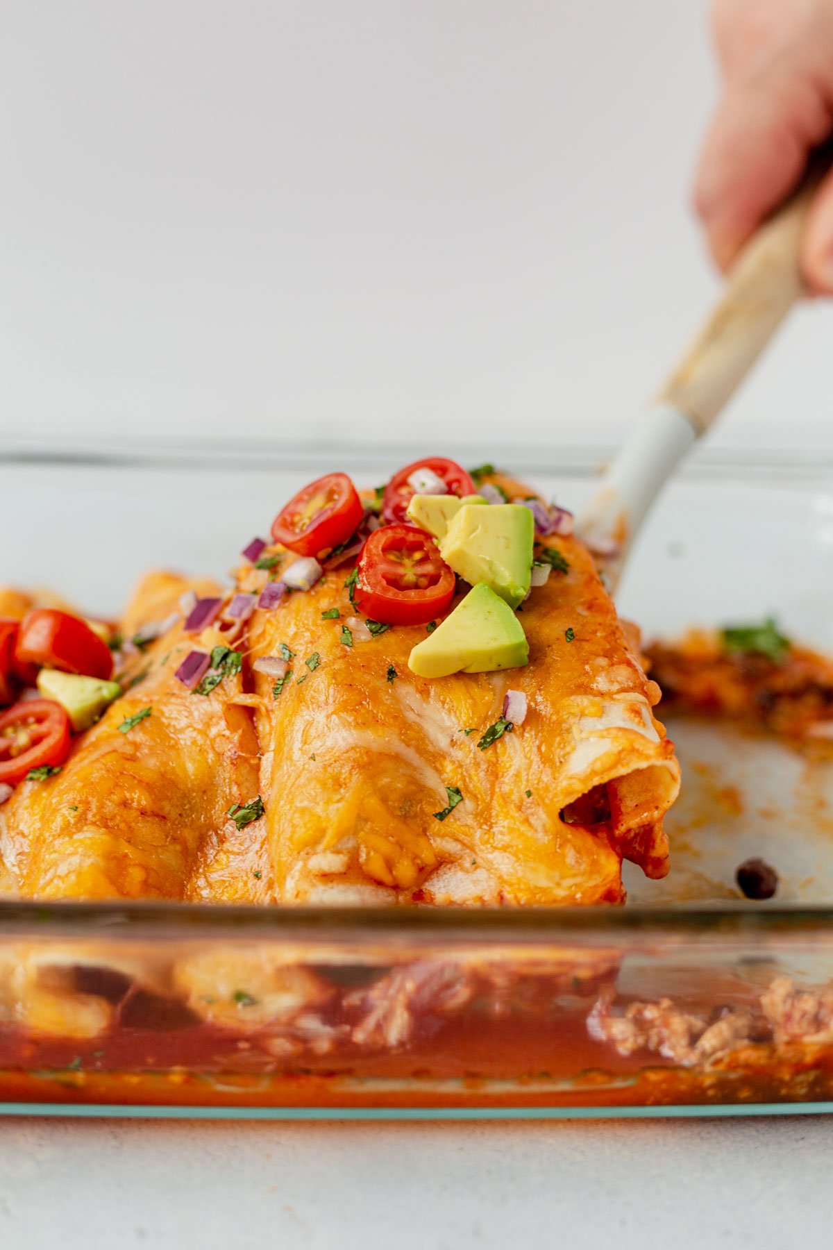 ground turkey enchiladas being pulled out of a pan