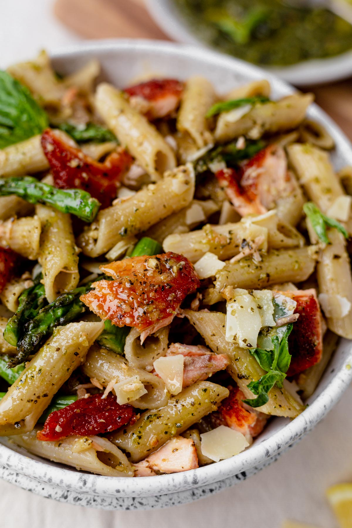 parmesan cheese and basil on top of salmon pesto pasta