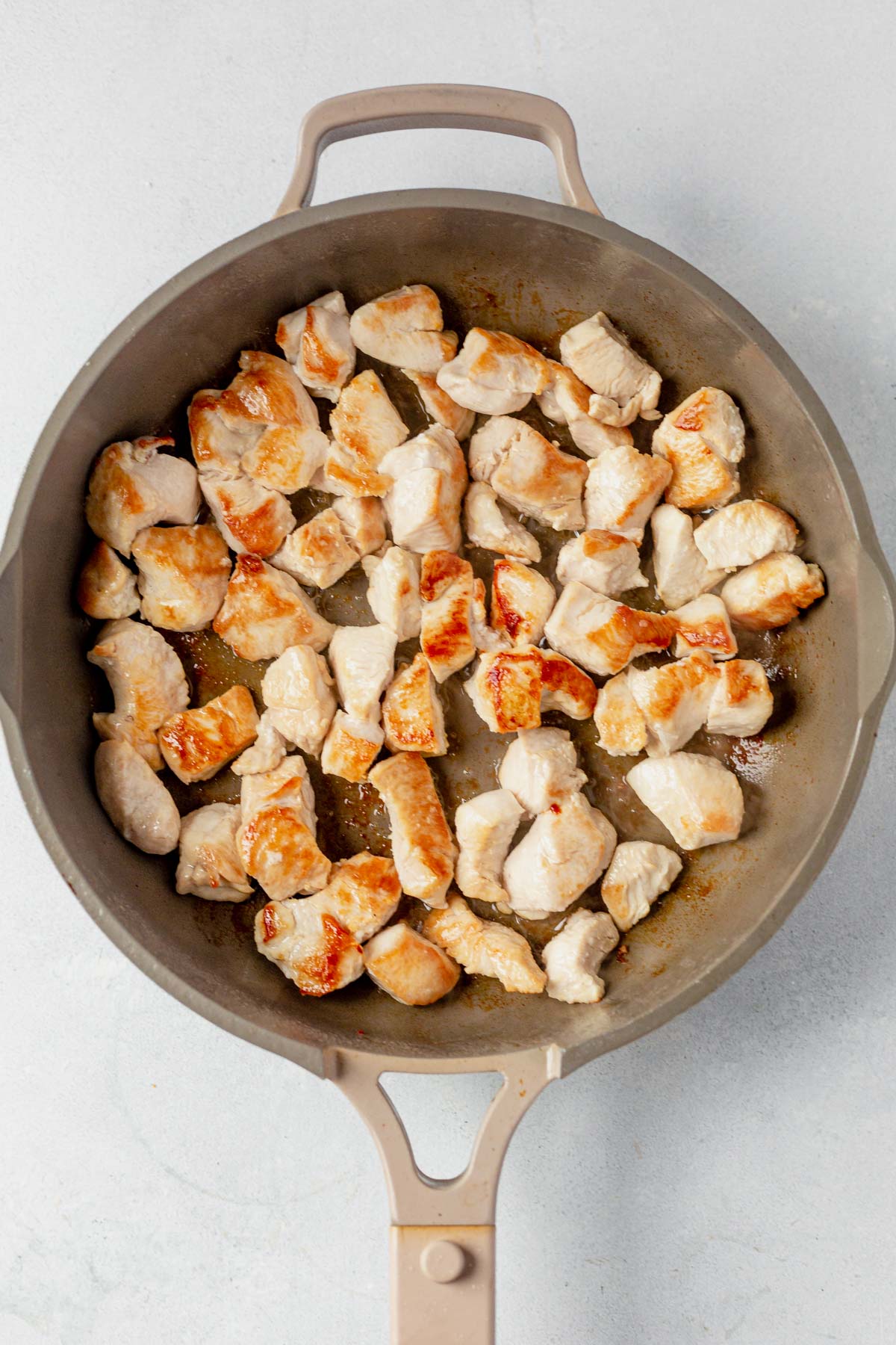 seared golden brown chicken chunks in a skillet