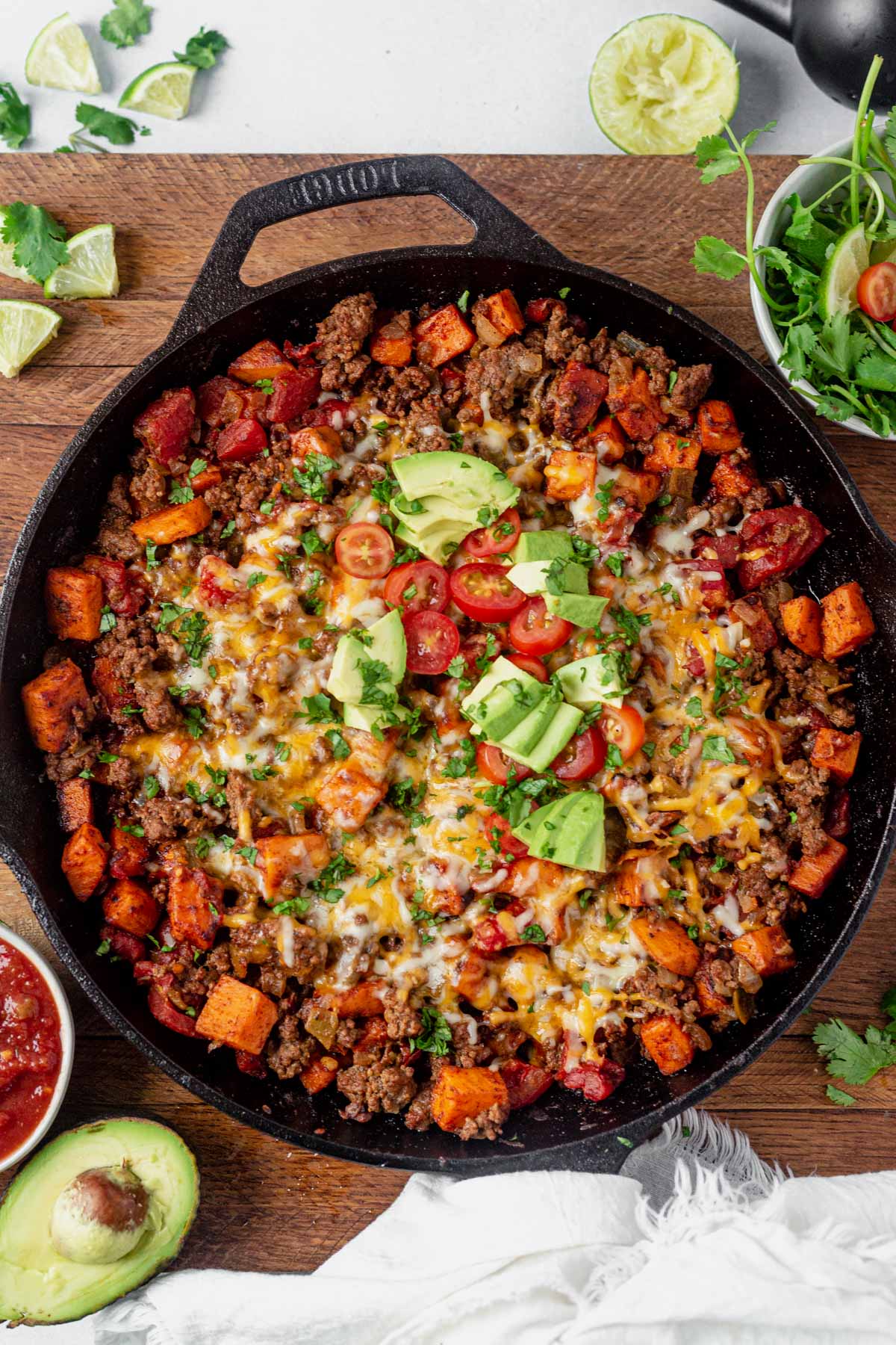 taco skillet topped with cheese, avocado and tomato