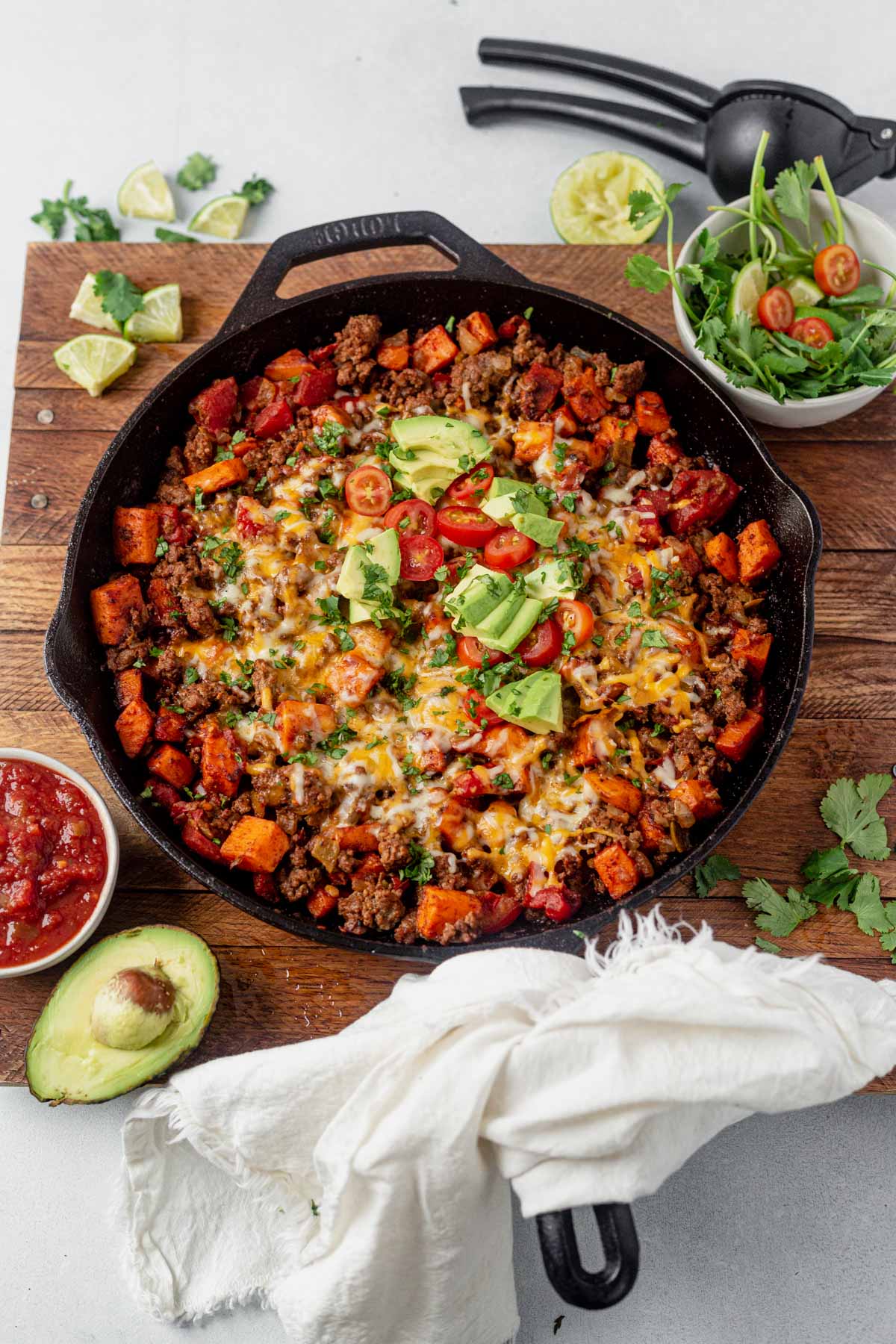 taco skillet in cast iron toopped with avocado, cheese and tomato