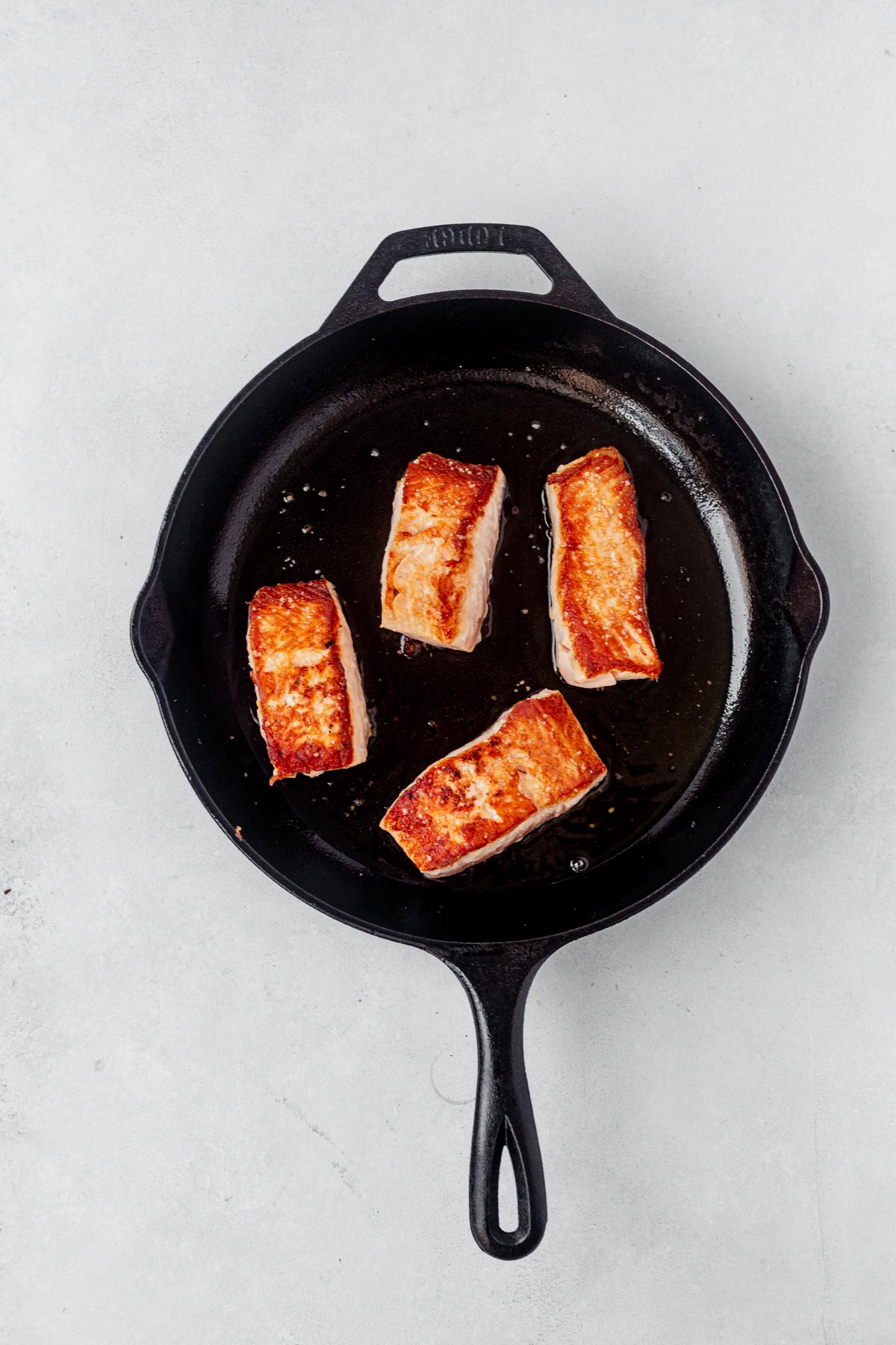 4 pieces of seared salmon in a cast iron skillet