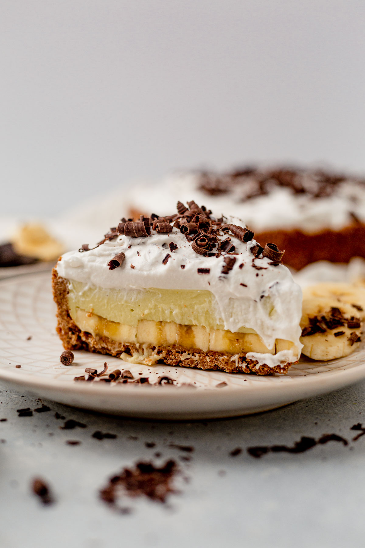 a slice of banana cream pie on a plate with chocolate shavings
