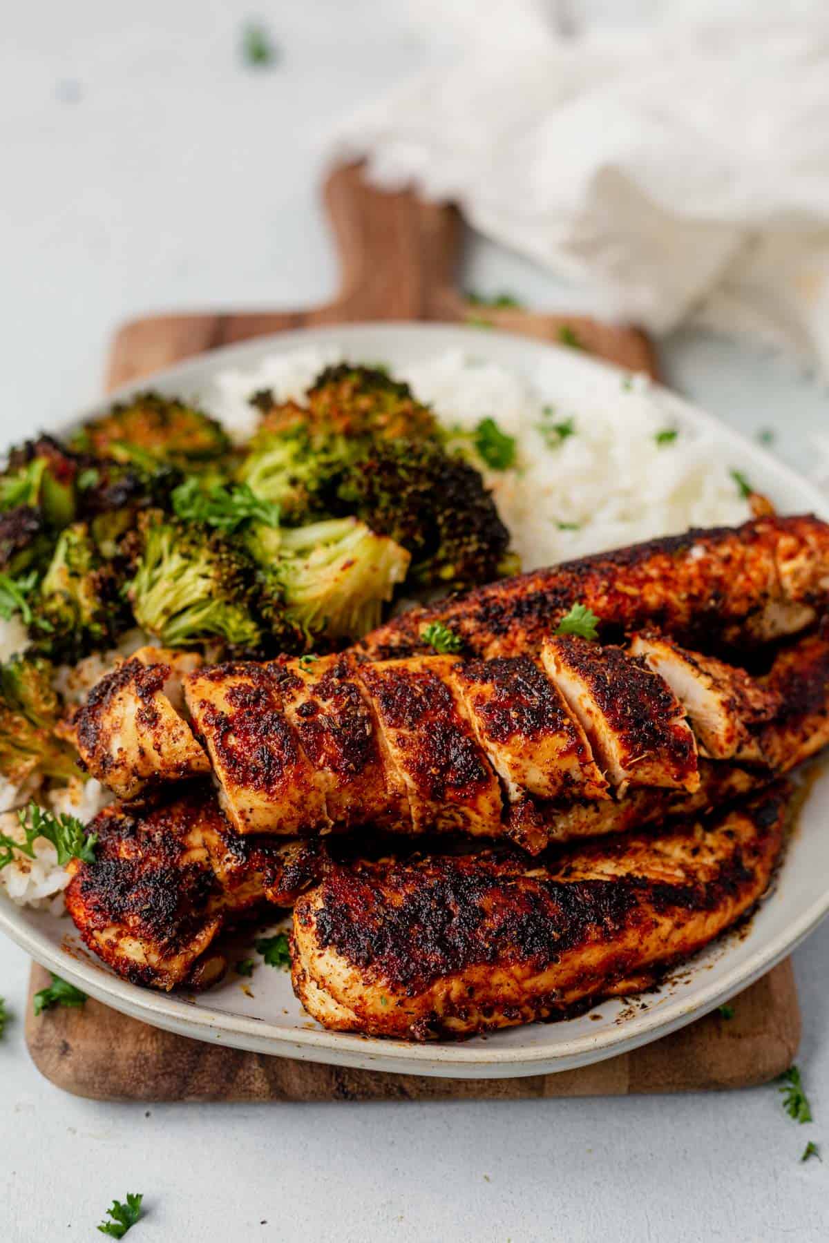 four blackened chicken tenders on a dinner plate with broccoli