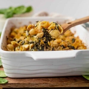 scooping out spinach artichoke pasta bake to serve
