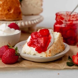 a piece of gluten-free angel food cake on a serving plate with strawberry compotee