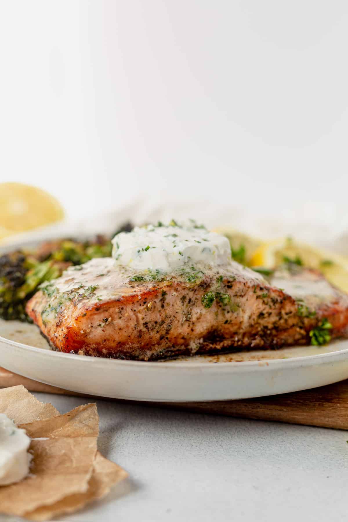 herb grilled salmon on a plate topped with herb garlic butter