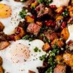 steak and potato breakfast hash with fried eggs, pepper and fresh parsley sauce