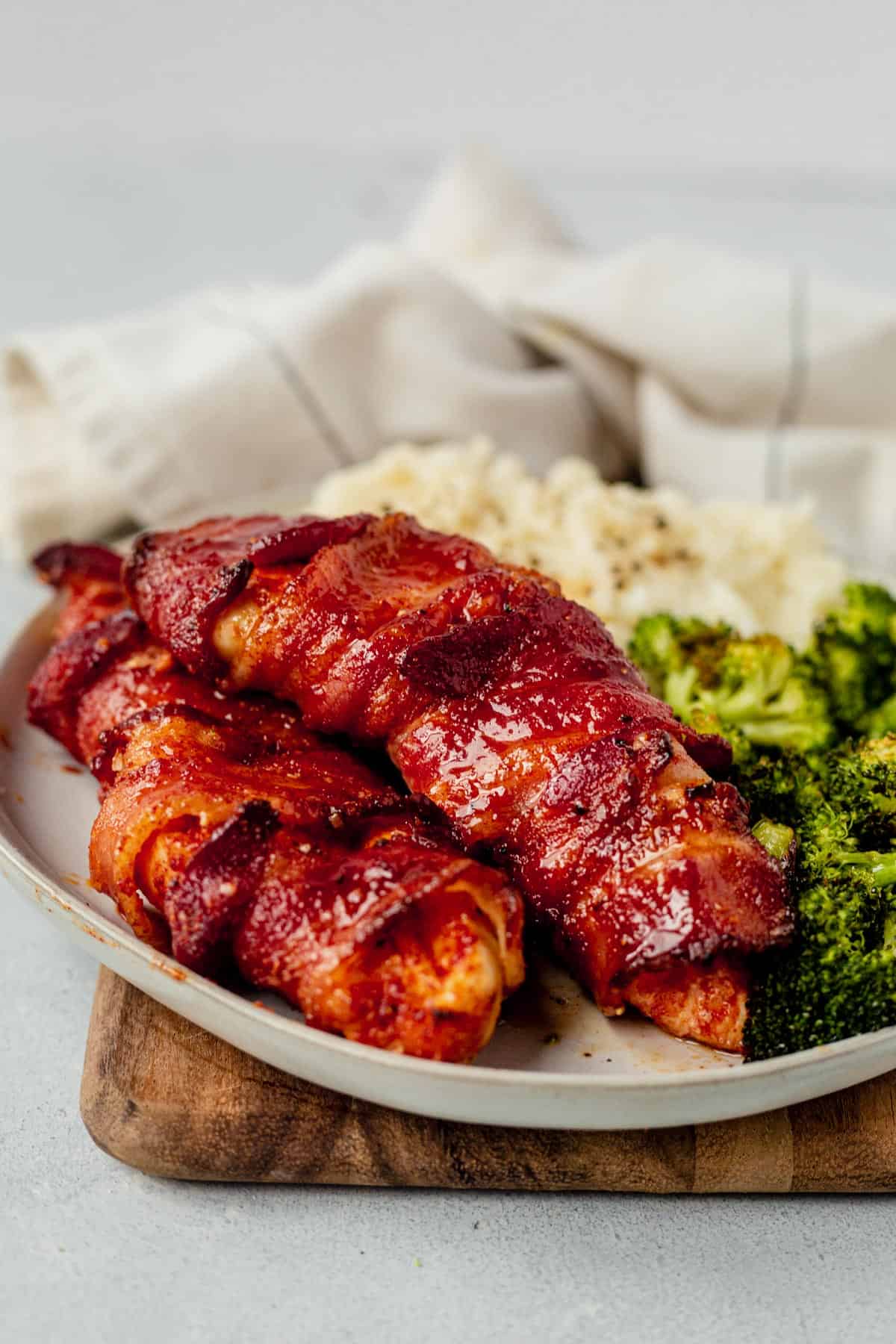 two pieces of air fryer bacon wrapped chicken breast on a plate with broccoli