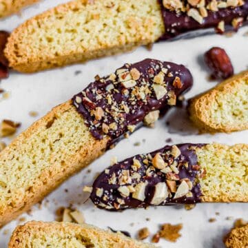 gluten free biscotti on parchment paper with melted chocolate and almonds