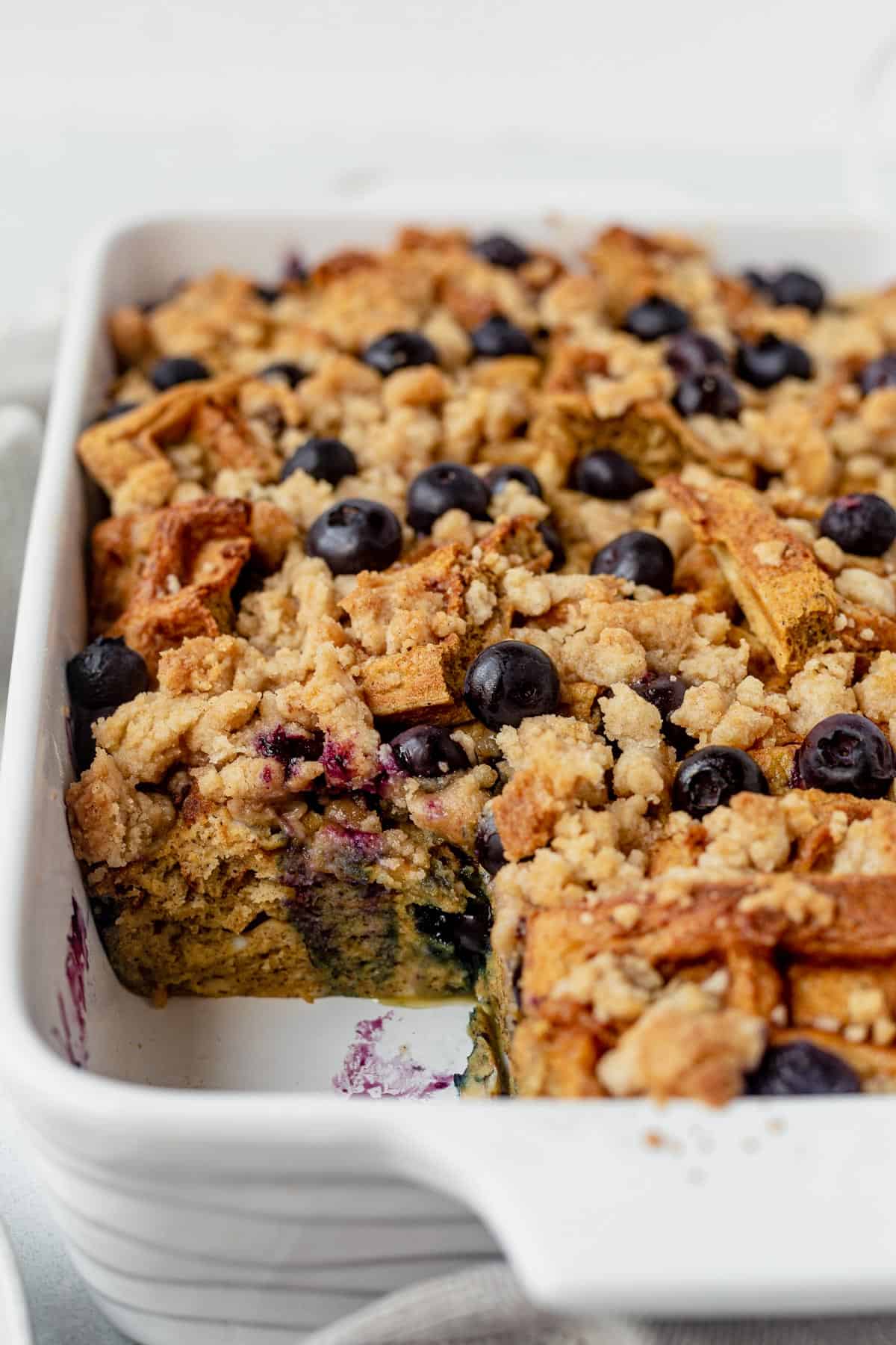 a slice of overnight blueberry waffle casserole taken out of a casserole dish