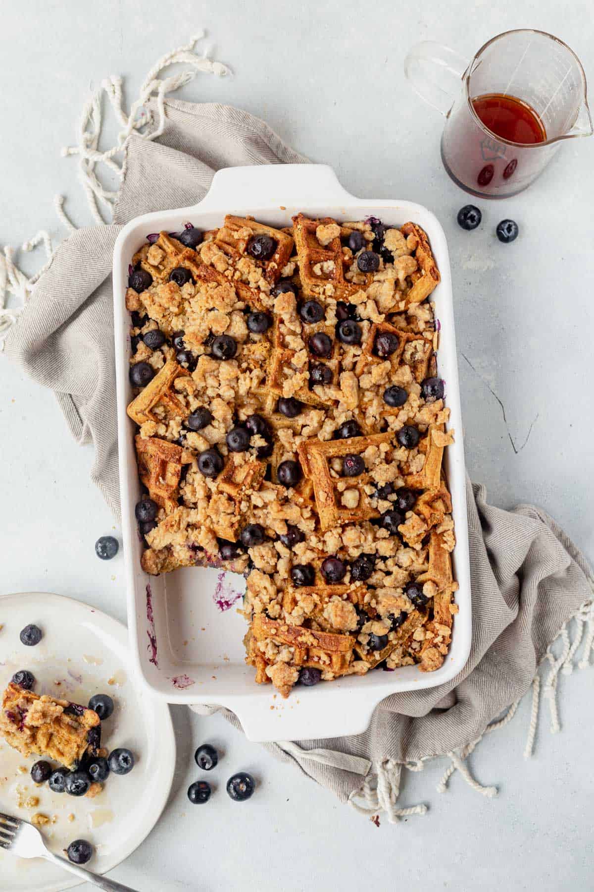 blueberry waffle casserole in a baking dish with maple syrup