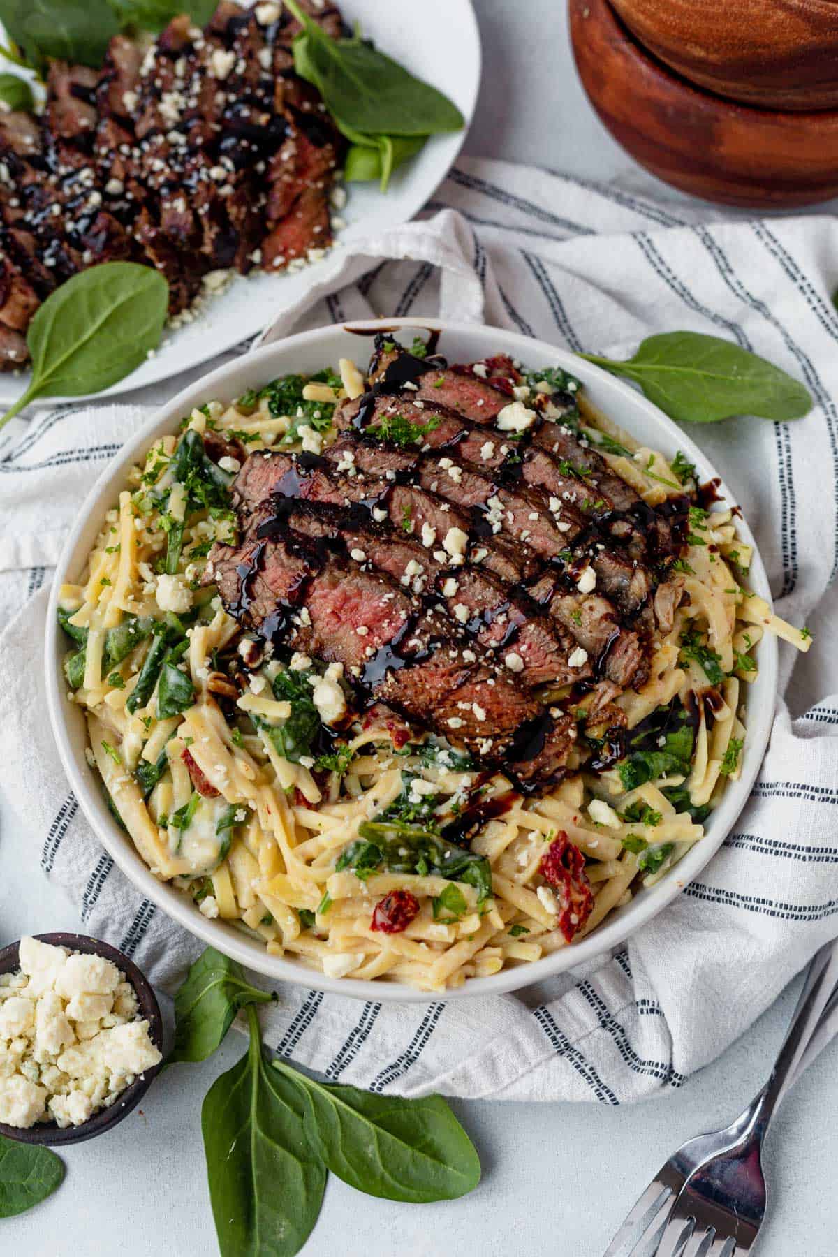 steak pasta in a bowl with gorgonzola cheese and balsamic glaze