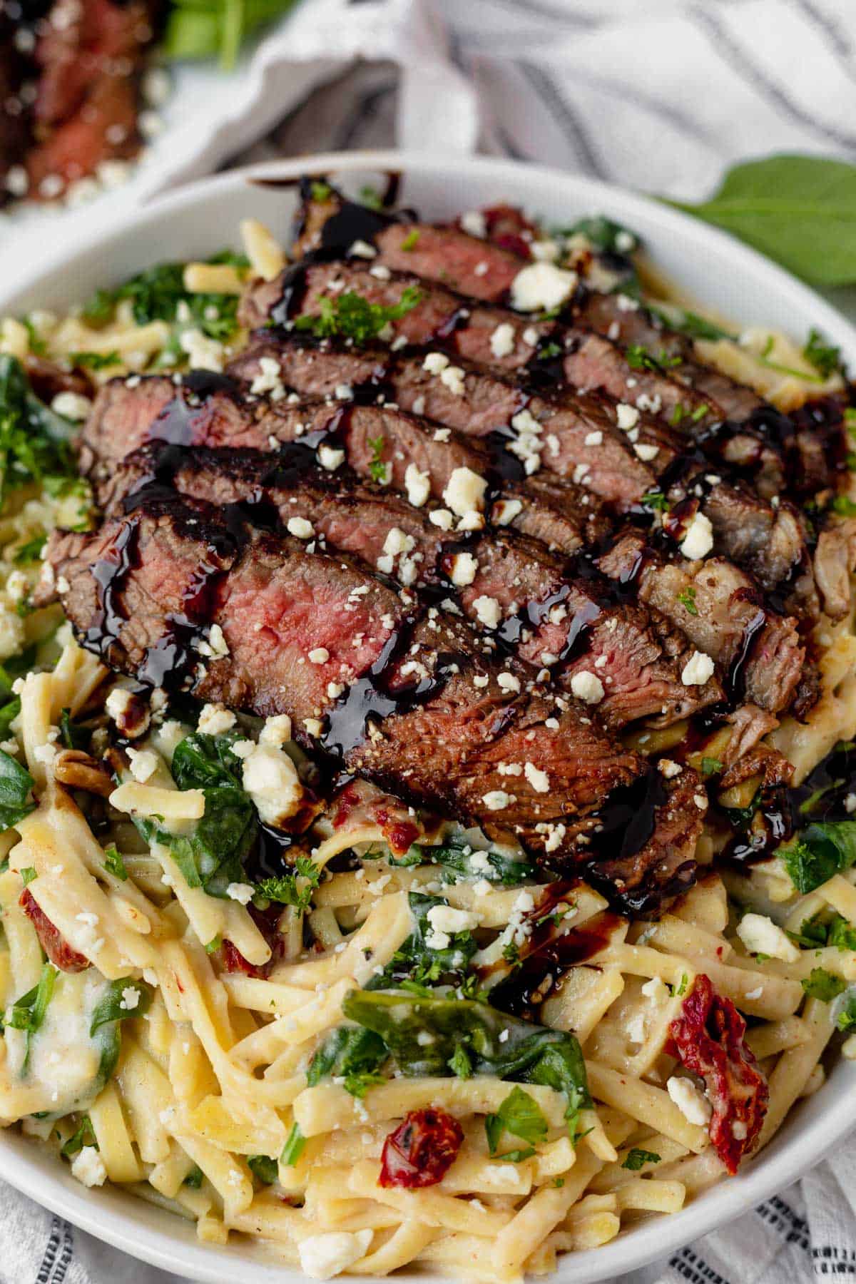 medium rare sliced steak on top of creamy pasta