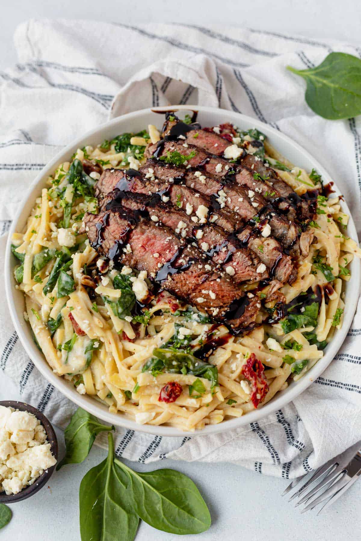 steak pasta in a white bowl with balsamic glaze