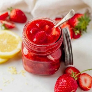 a jar of strawberry compote with a spoon
