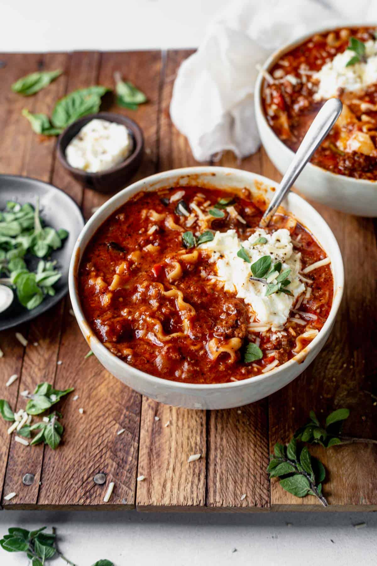 a bowl of instant pot lasagna soup topped with basil and ricotta cheese