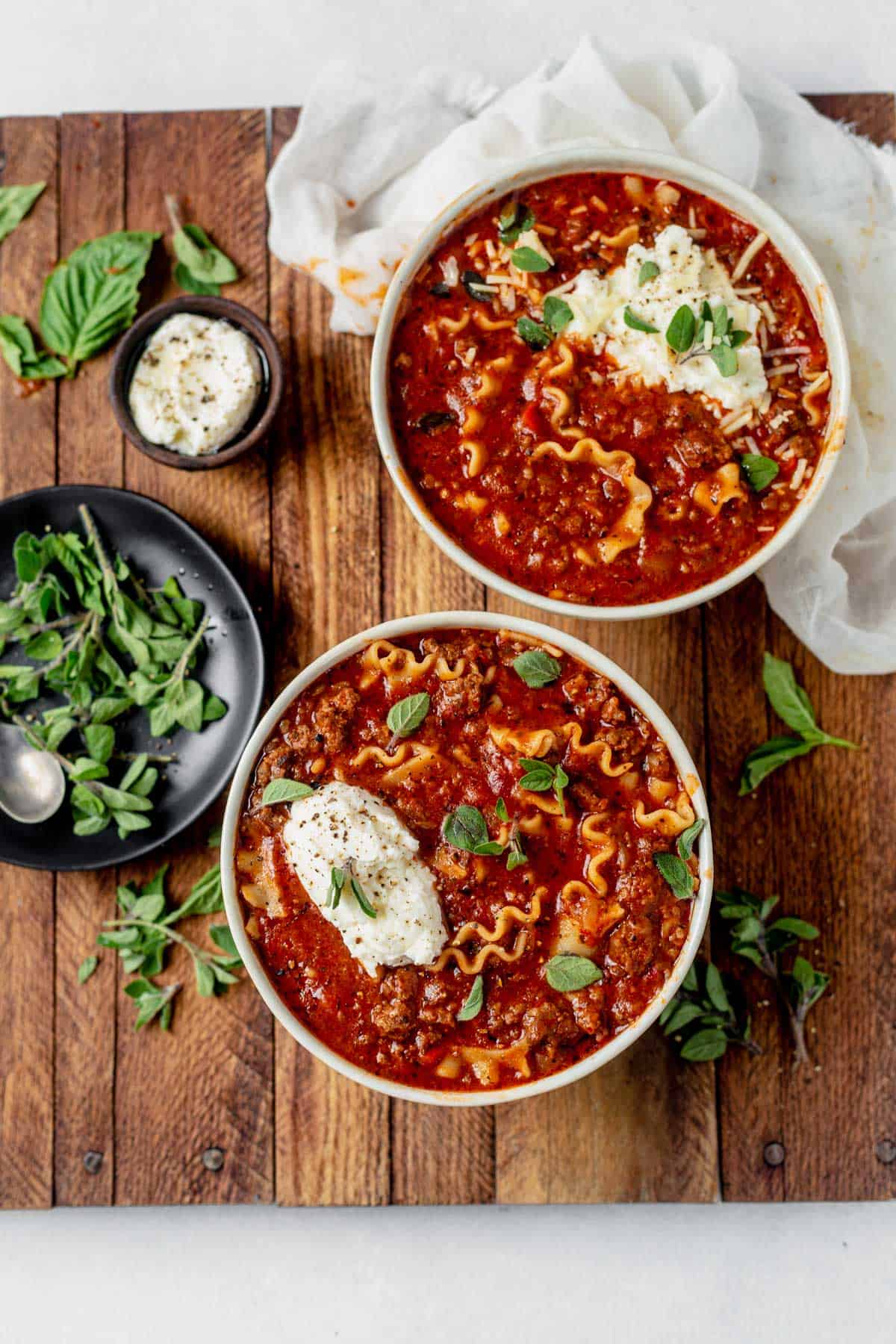 two bowls of lasagna soup with fresh basil and cheese
