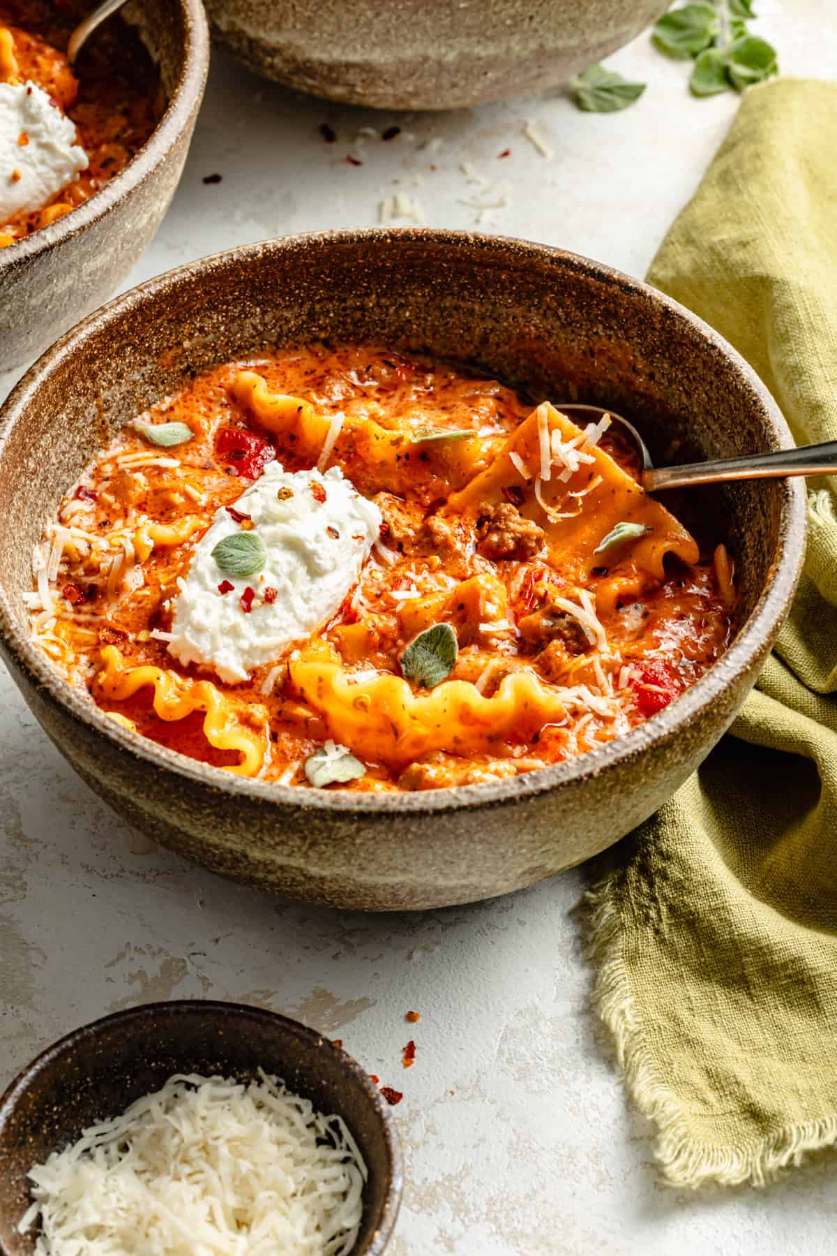 a bowl of instant pot lasagna soup topped with ricotta and basil.