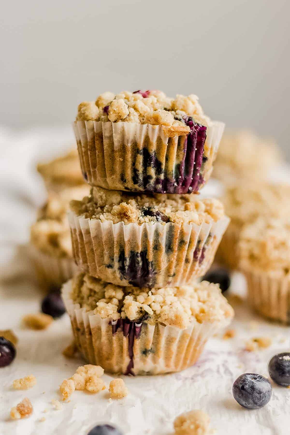 three blueberry crumb muffins stacked on top of each other