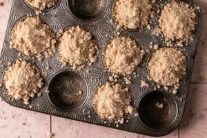 unbaked blueberry muffins with crumb topping in a muffin pan