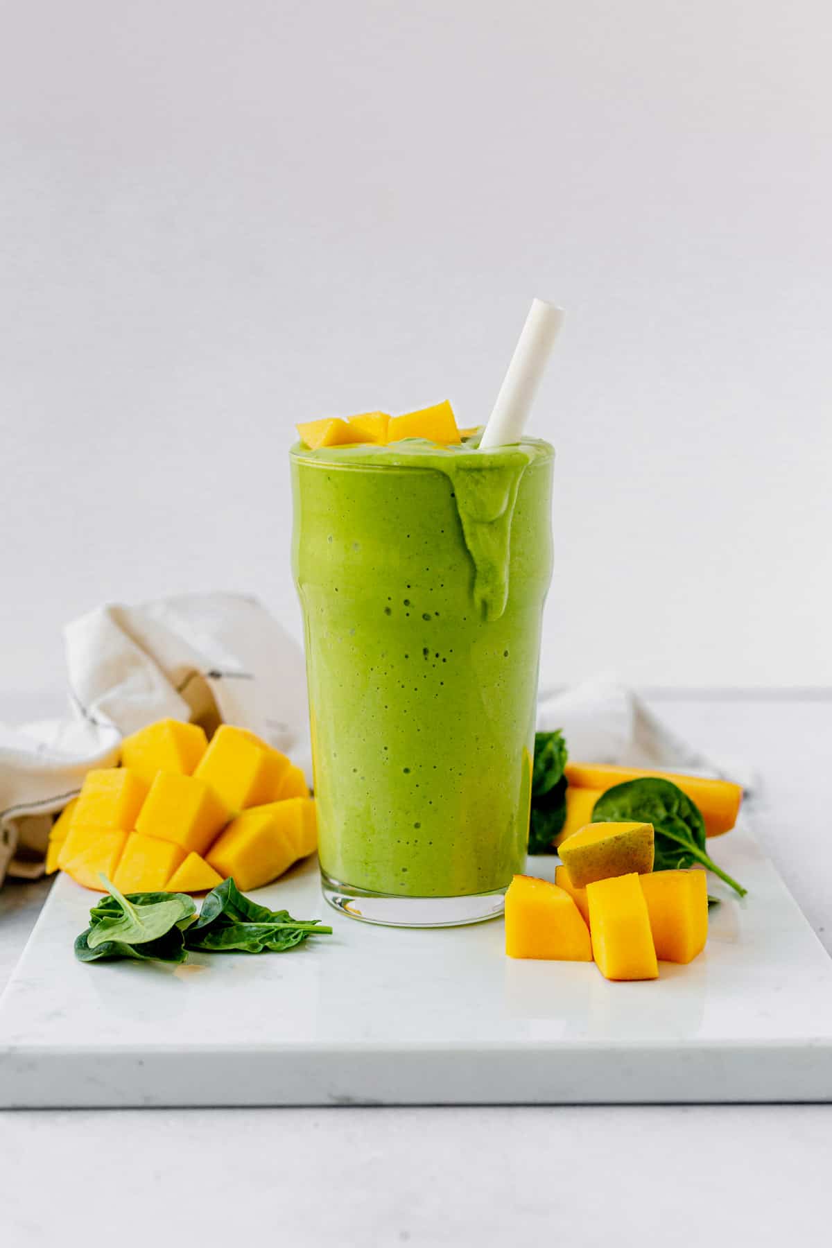 mango spinach smoothie dripping over the side of a glass