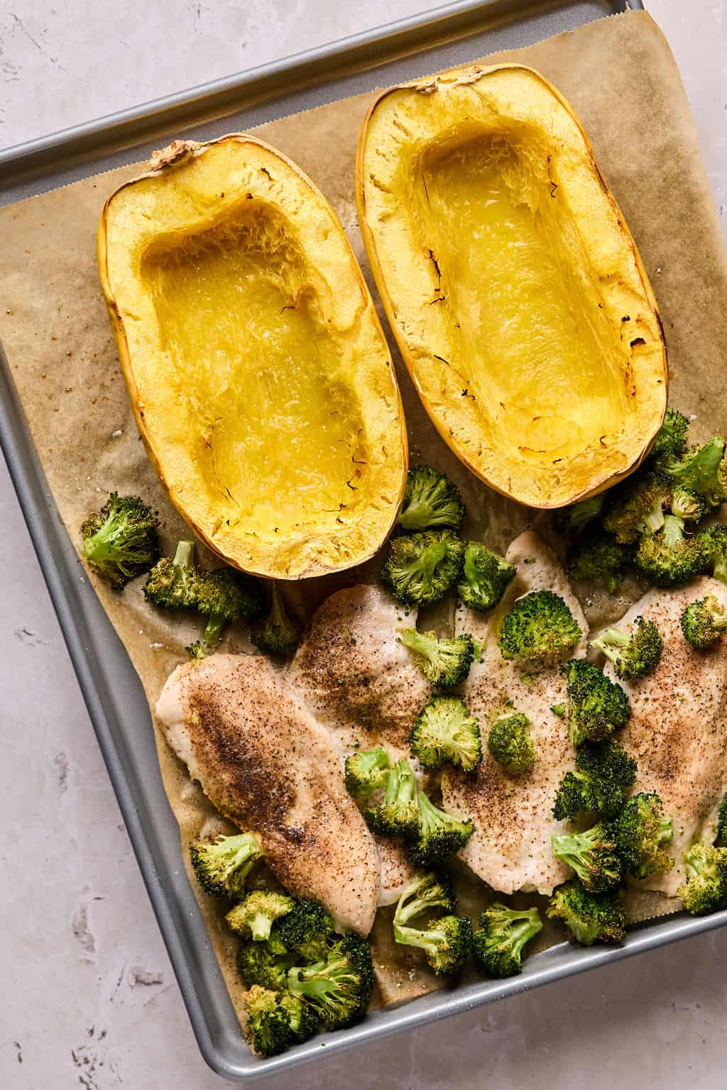 baked chicken, broccoli, and spaghetti squash on a baking sheet.