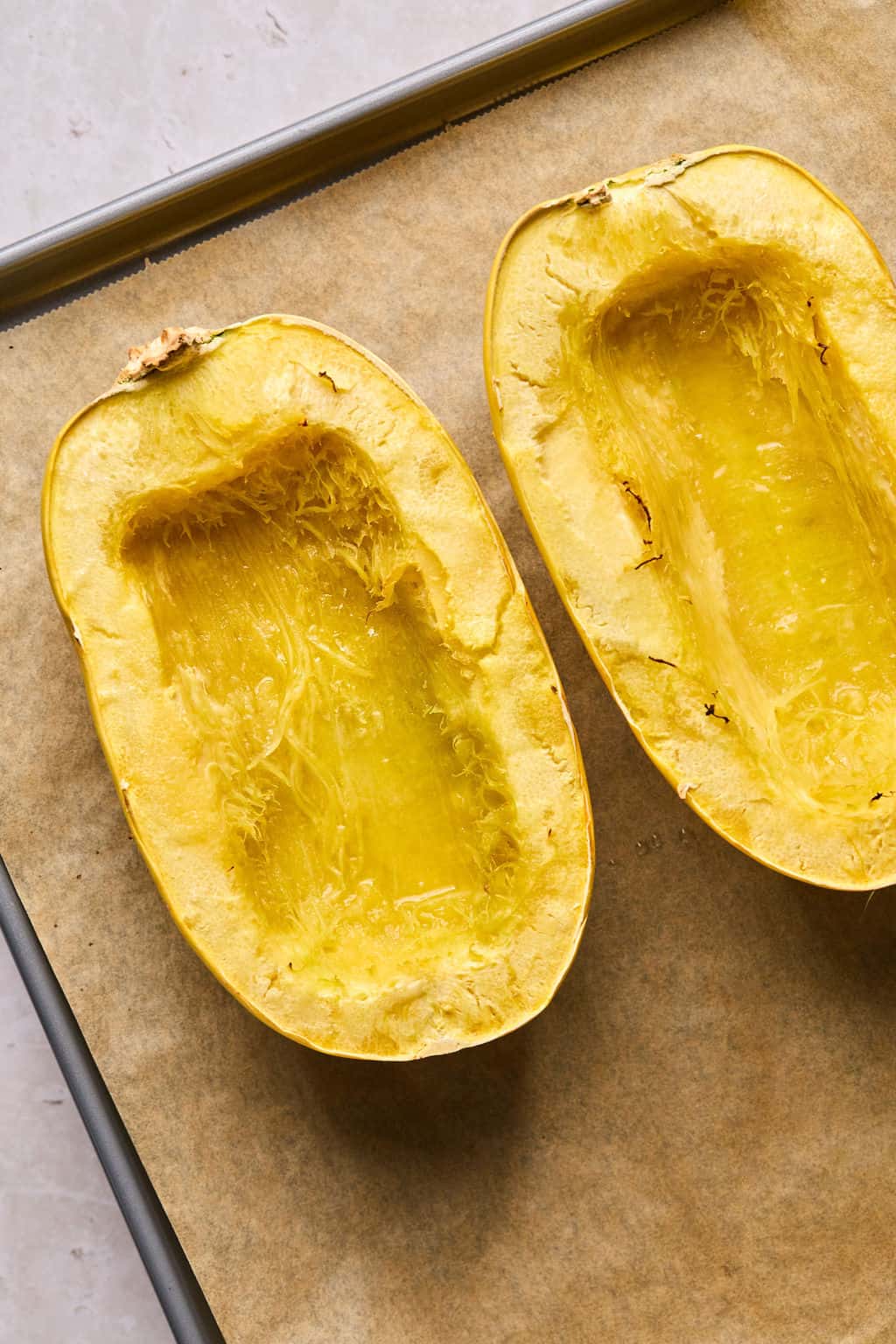 spaghetti squash roasted on a parchment lined baking sheet.