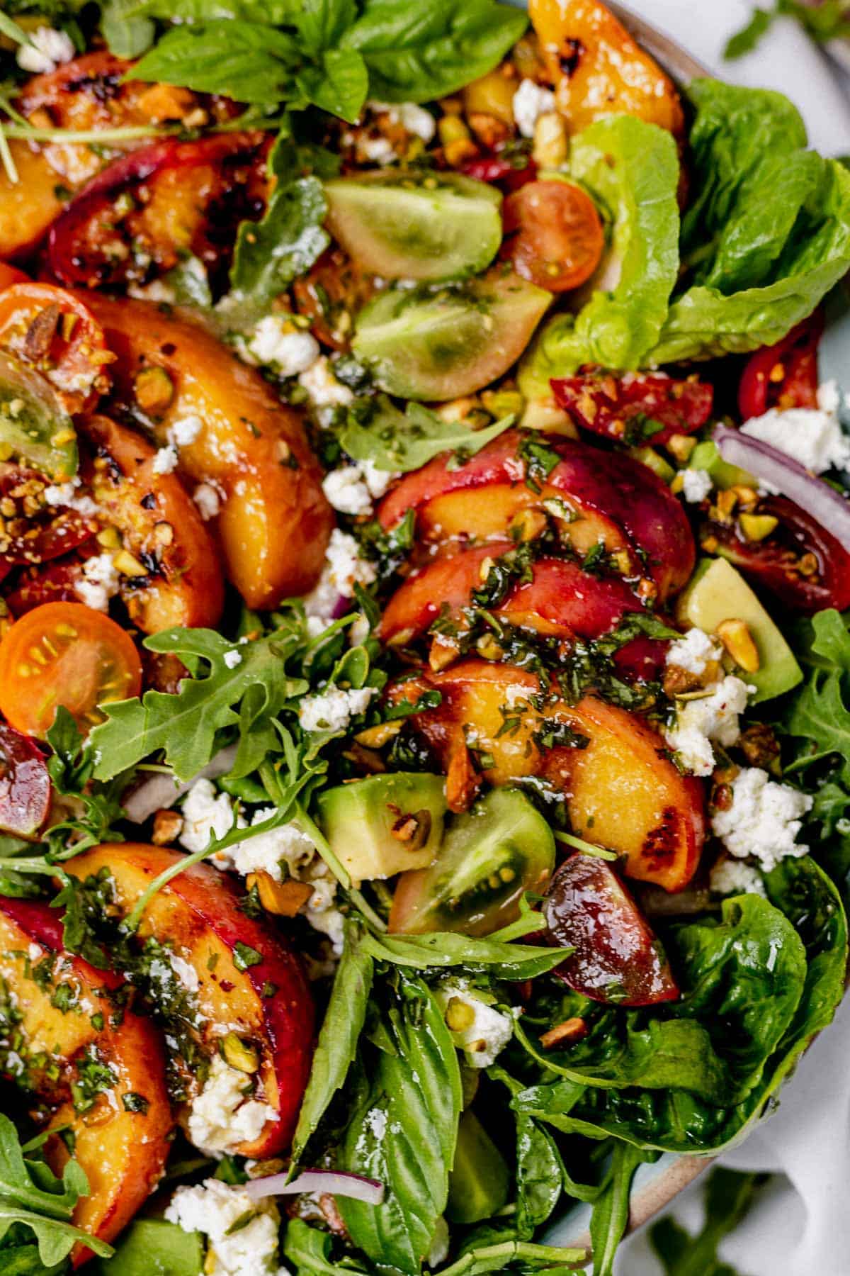 grilled peaches on top of mixed greens with tomatoes, goat cheese and basil