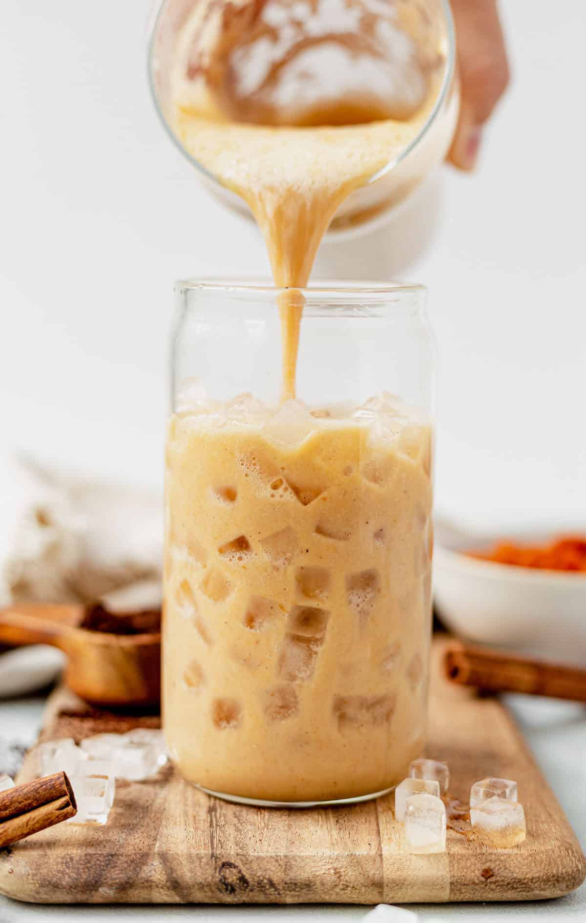 pouring pumpkin spice latte over ice.