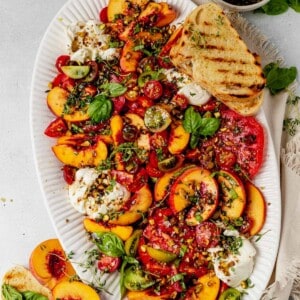 peach burrata salad on a platter with crusty bread