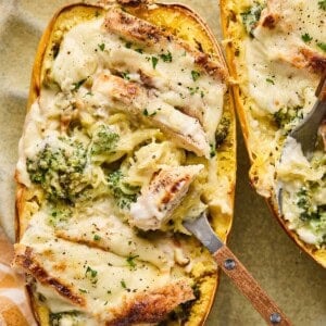 two spahgetti squash chicken alfredo boats on a plate with a fork.