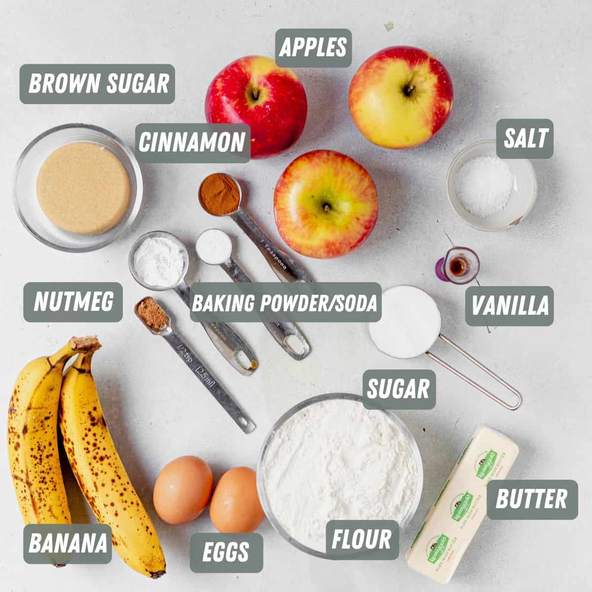 bananas, eggs, flour, butter, sugar, brown sugar, apples, cinnamon and leavens on a table