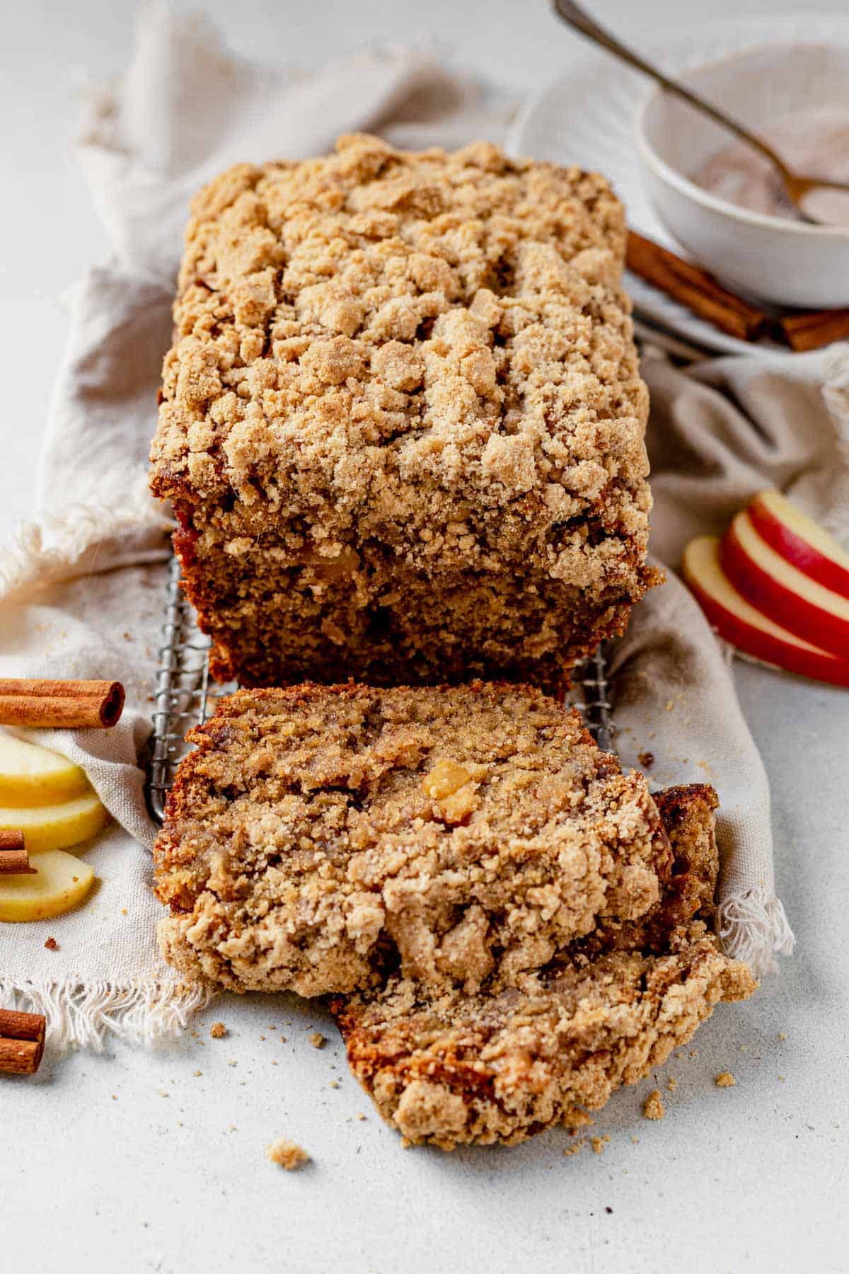 a loaf of apple banana bread on a cooling rack with two slices cut and laying on the table