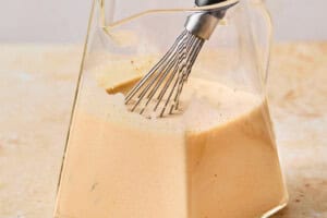 whisking homemade pumpkin cream cold foam in a glass cup.