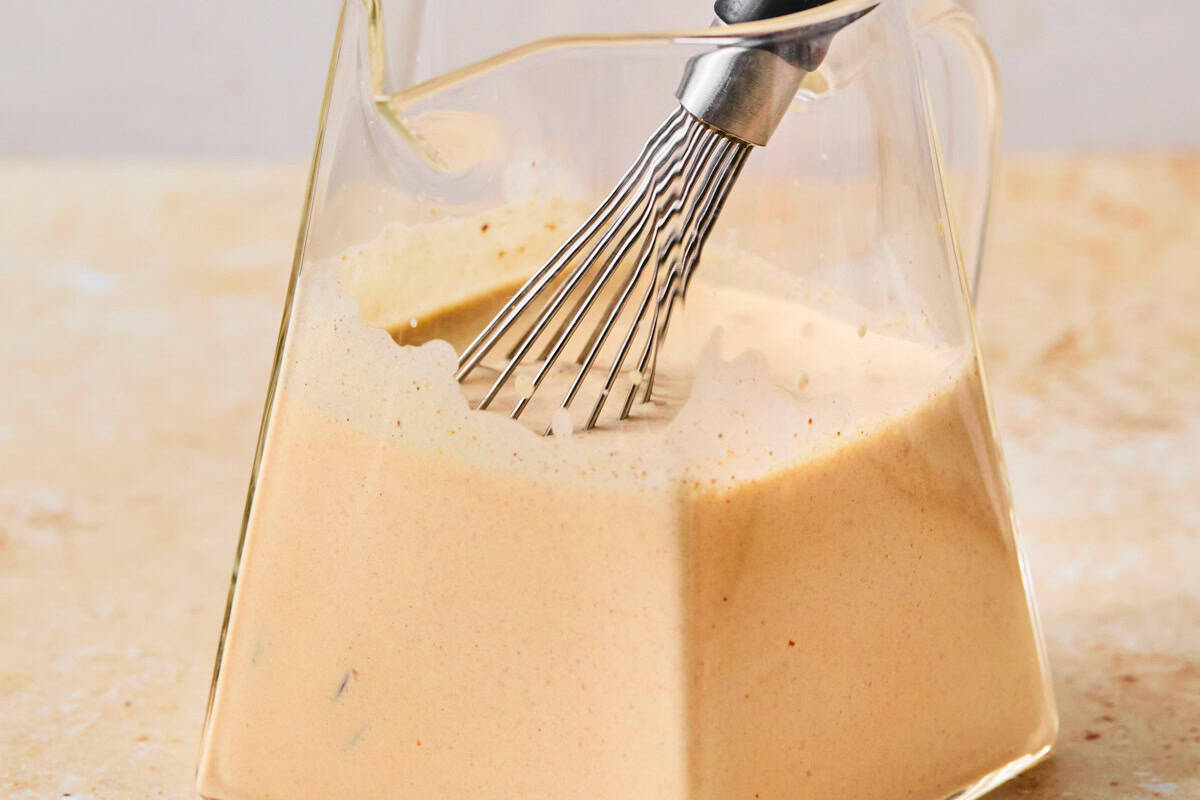 whisking homemade pumpkin cream cold foam in a glass cup.