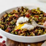 a poached egg yolk broken on top of brussel sprout hash