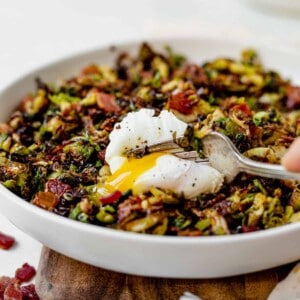 a poached egg yolk broken on top of brussel sprout hash