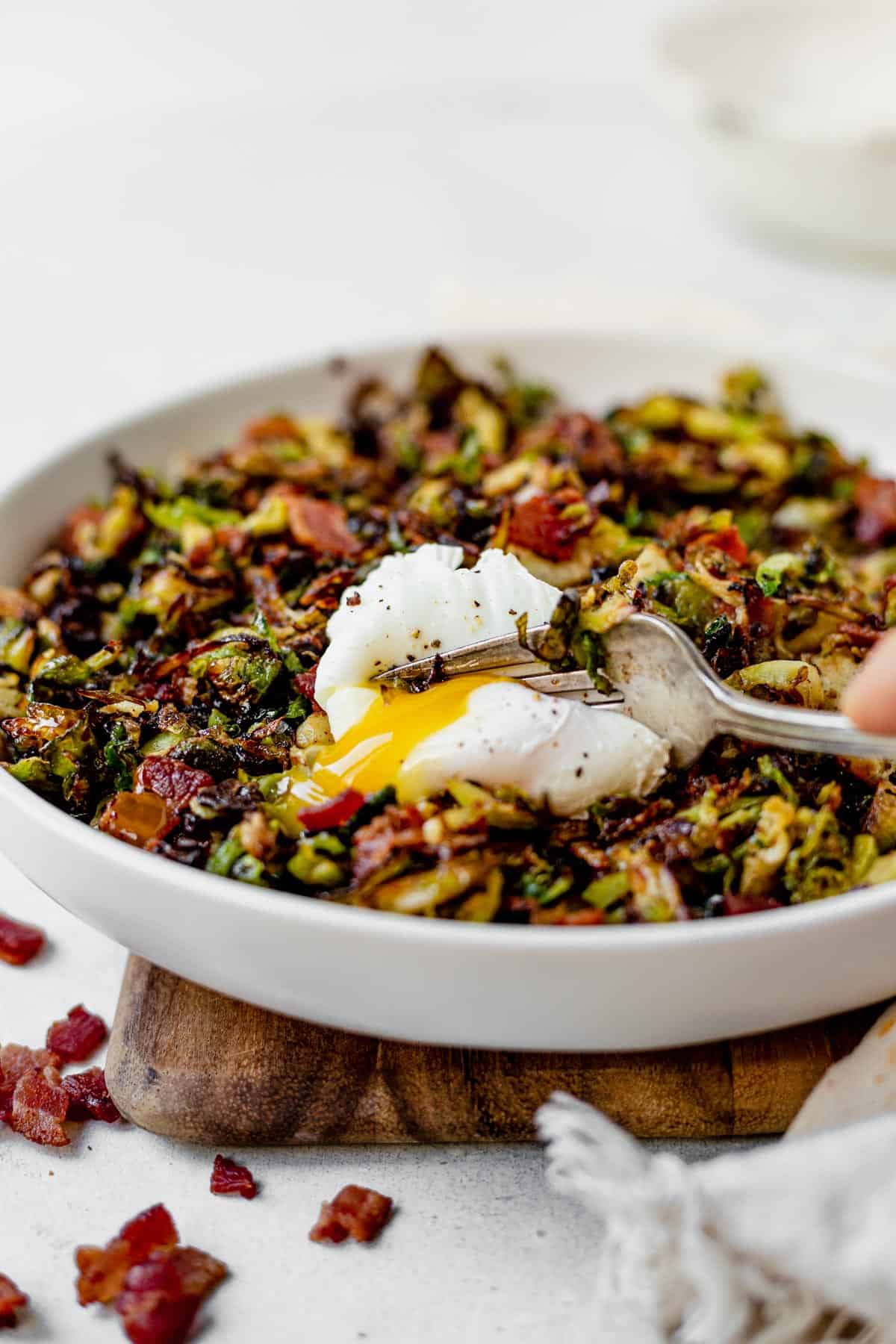 fork cutting into a poached egg on top of brussel sprout hash