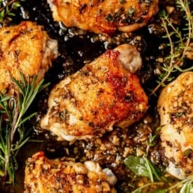 crispy chicken thighs with herbs in a cast iron skillet